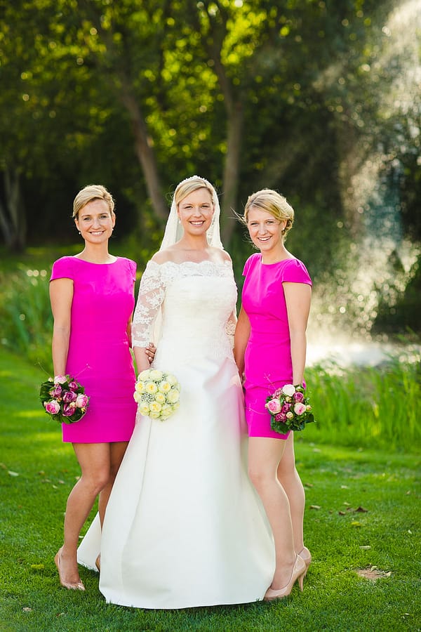 Foto der Braut mit ihren zwei Schwestern beide im gleichen Kleid draußen im Rahmen der Gruppenfotos für die Hochzeit