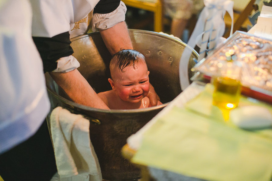 Kind wird weinend im Taufbecken getauft