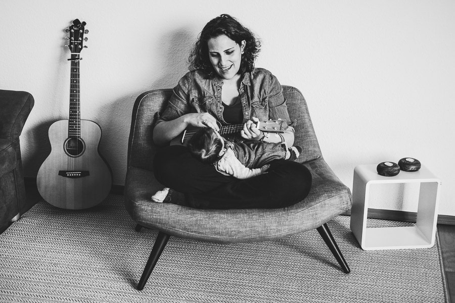 mutter spielt ihrem baby okulele gitarre im hintergrund