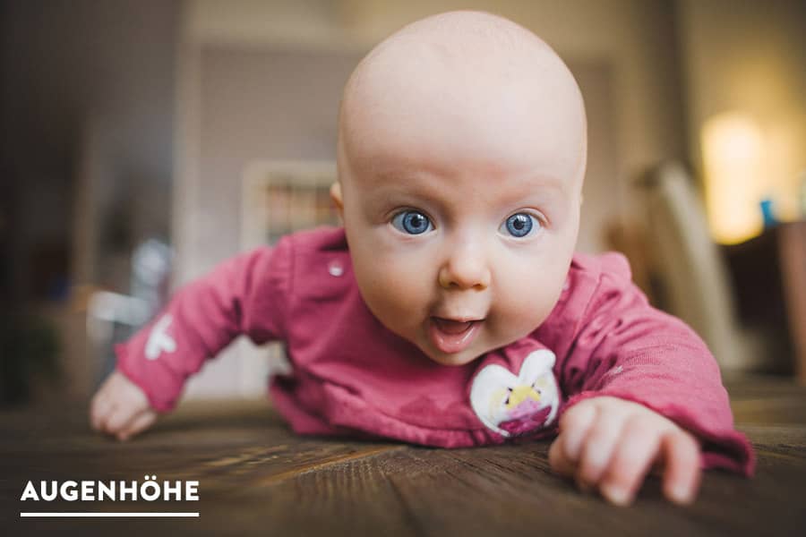 Baby auf krabbelt auf Holztisch fotografiert auf Augenhöhe