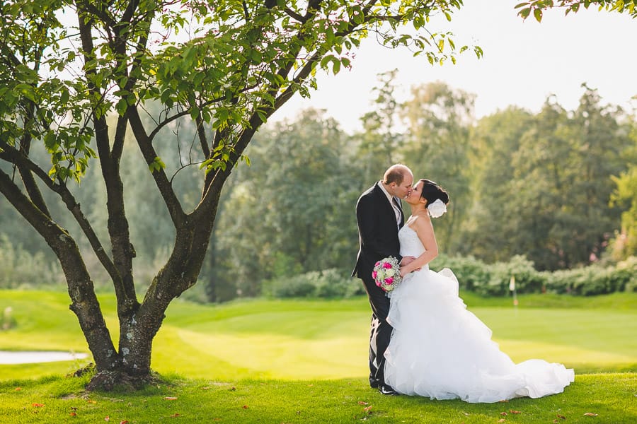 Brautpaar küsst sich auf Golfrasen von der Hochzeitslocation Kosaido in Düsseldorf erstrahlt vom stimmungsvollen Licht