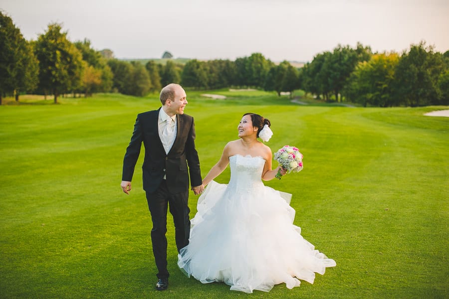 Chinesische Braut und deutscher Bräutigam als Brautpaar laufen glücklich aufm gepflegten Rasen von Golfclub Kosaido in Düsseldorf